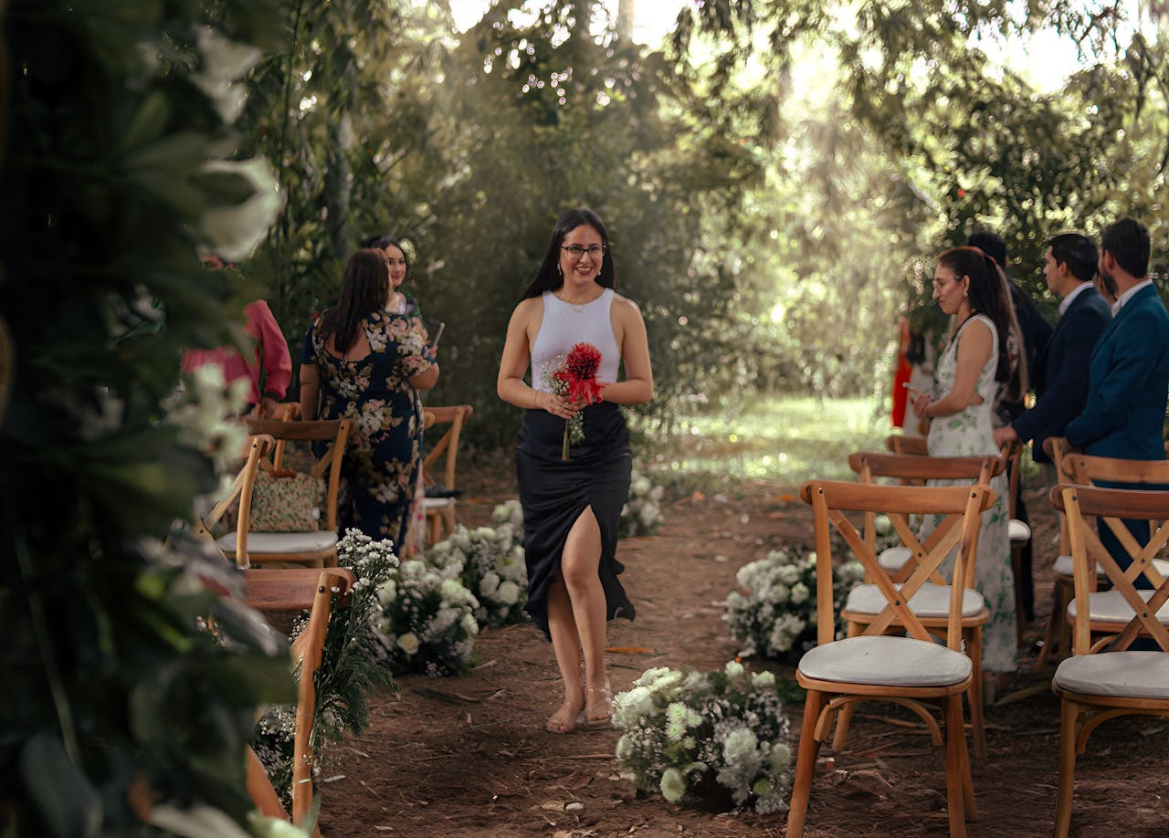 Outdoor wedding ceremony with bridesmaid walking down the aisle in a summer setting.