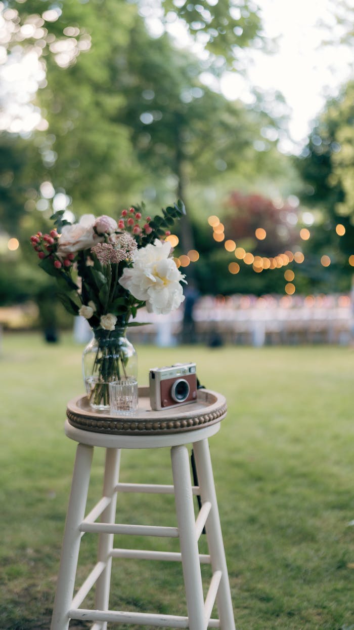A charming bouquet and vintage camera on a stool in a garden setting, ideal for wedding themes.